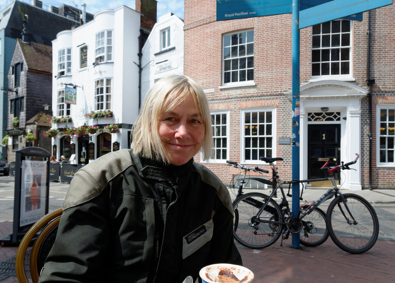 Cathy enjoying a cup of coffee in 'The Lanes' while over her shoulder is a local 16th Century Inn.